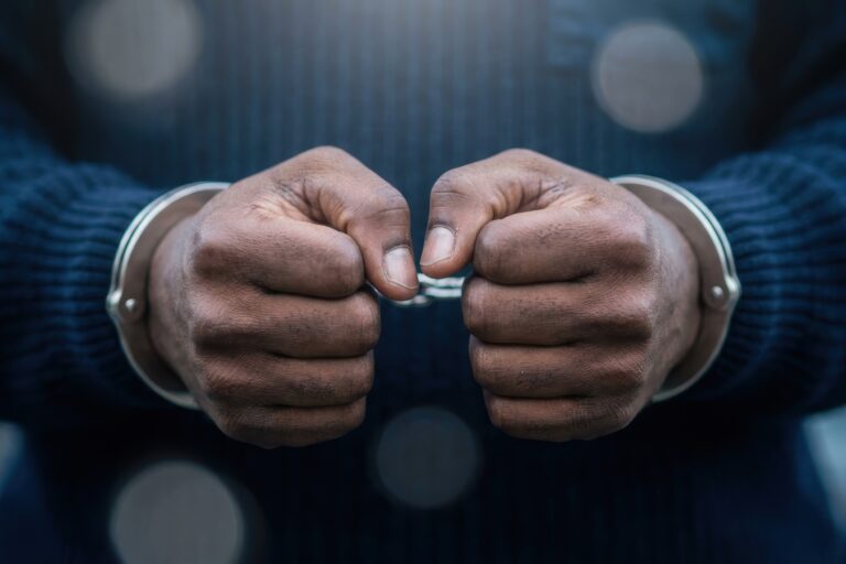 Close-up of a person's hands in handcuffs, symbolizing arrest, guilt, and the justice system.