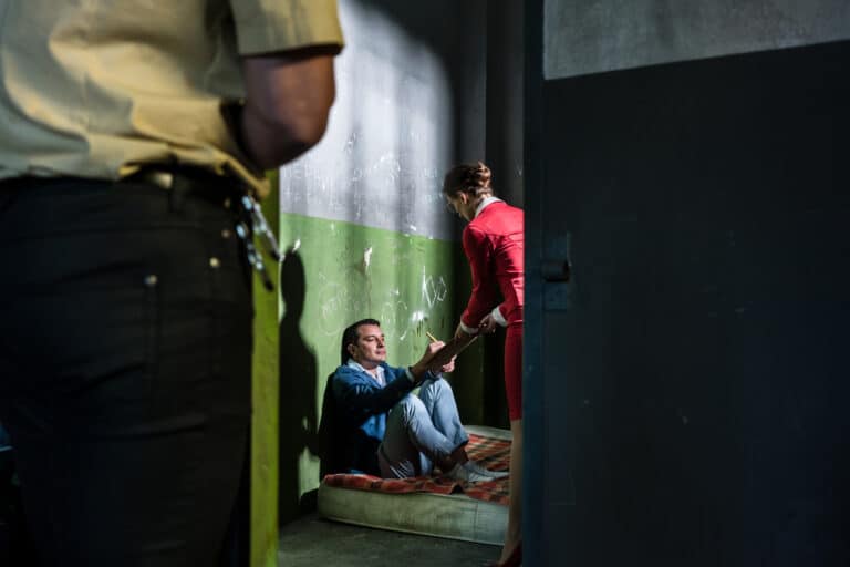 Dedicated female attorney visiting a young male inmate while helping him with the legal procedures in an obsolete prison cell during custody