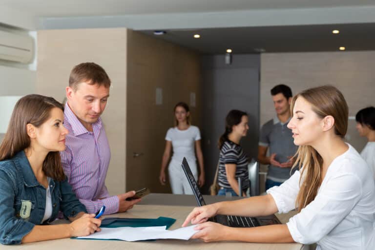 Young female employee of staffing agency consulting clients at meeting in informal office interior