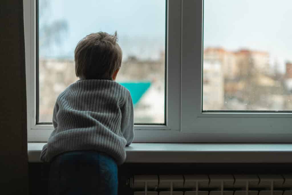 The child clouds at the window sill and looks out the window